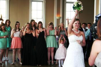 The bride is about to toss her bridal bouquet to all of the single girls at the Adelaide Hall in Fort Smith, Arkansas.